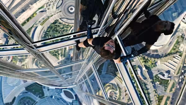 Ethan Hunt (Tom Cruise) and another climbing a glass tower facade