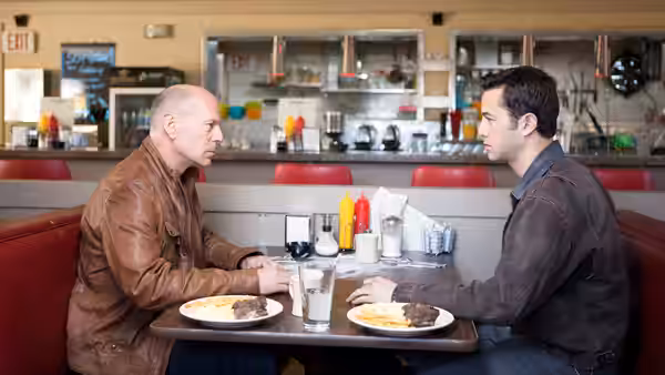 Joe (Joseph Gordon-Levitt) and Old Joe (Bruce Willis) talking across a diner table