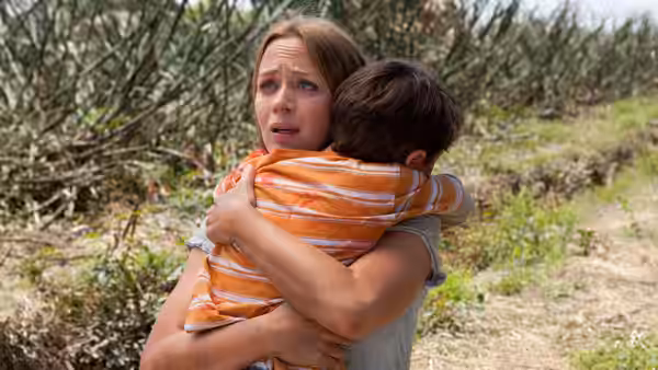 Sara (Emily Blunt) hugging a boy in a field