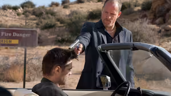 Charlie (Woody Harrelson) pointing a gun at Marty in a desert car