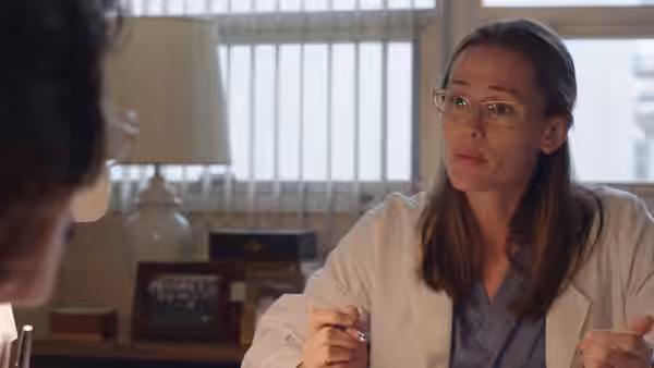 Eve (Jennifer Garner) gestures while speaking in office with lamp and files