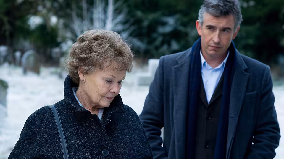 Philomena (Judi Dench) and Martin Sixsmith (Steve Coogan) stand in a snowy graveyard