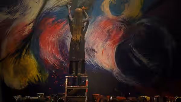 An artist standing on a ladder painting a large colorful mural