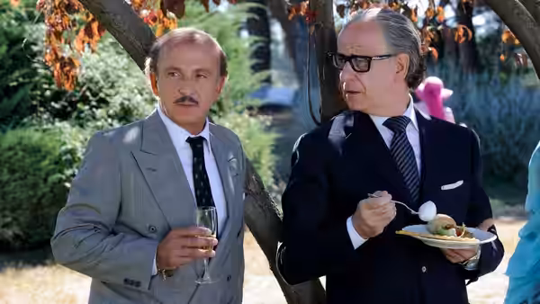 Jep Gambardella (Toni Servillo) standing outdoors with a man holding a plate