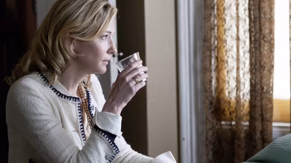 Jasmine (Cate Blanchett) holding a glass while gazing out a window