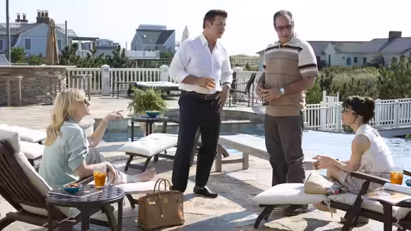 Four people talking on a patio beside a swimming pool