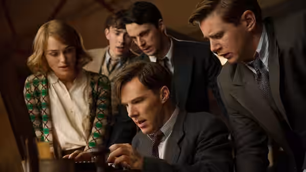Alan Turing (Benedict Cumberbatch) and Joan Clarke (Keira Knightley) studying papers with colleagues