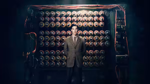 Alan Turing (Benedict Cumberbatch) standing before a wall of rotors and cables