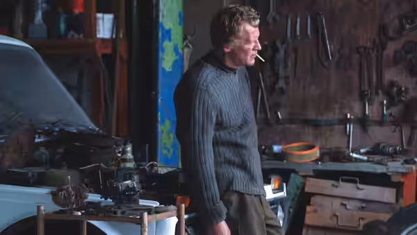 a man smoking a cigarette inside a cluttered workshop