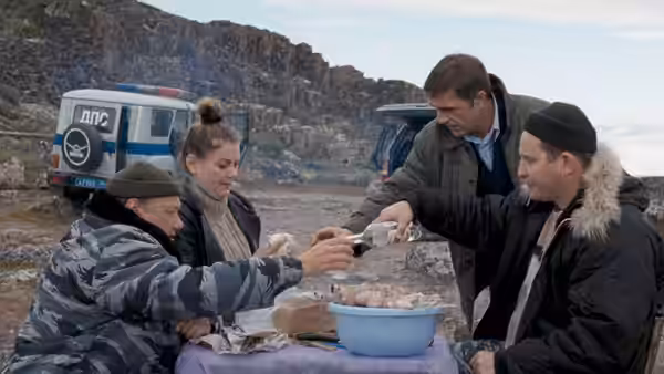 four people sharing drinks at a table outdoors near vehicles