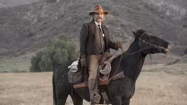 Man in brown suit and hat seated on a black horse