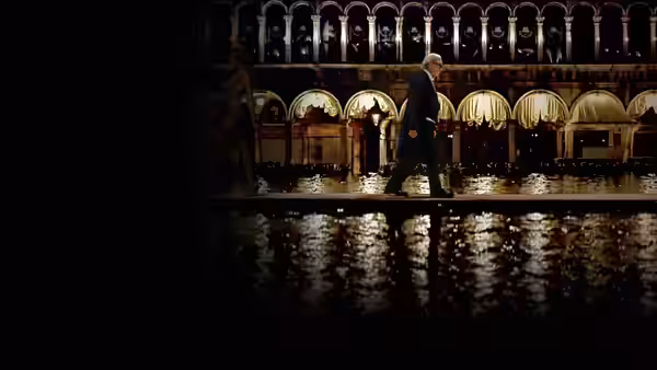Man in a suit walking across a wet plaza at night