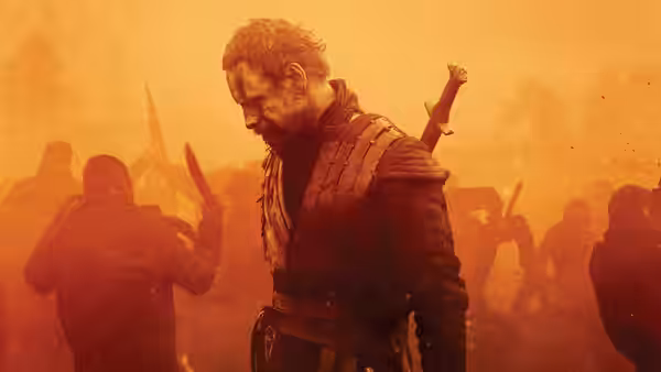 Macbeth (Michael Fassbender) standing amid warriors in a smoky battlefield
