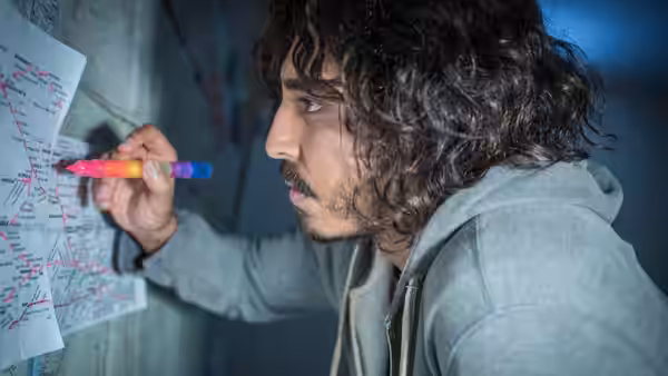 Saroo Brierley (Dev Patel) marking a map on the wall with a pen