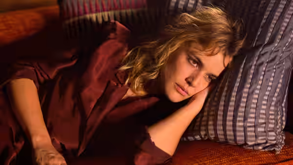 Julieta (Adriana Ugarte) reclines on a bed in a maroon satin robe