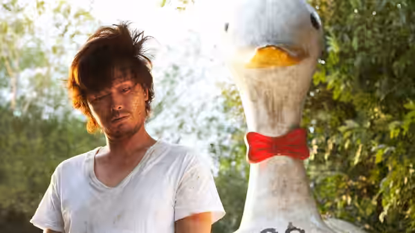 Mr. Kim (Jung Jae-young) looks down at a white duck figure with a red bow tie