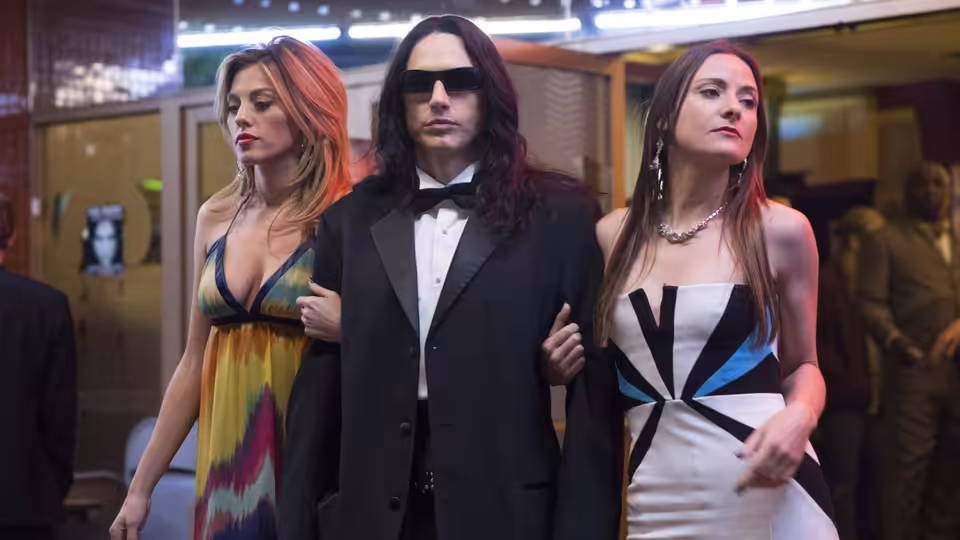 Tommy (James Franco) walking arm in arm with two women in evening wear