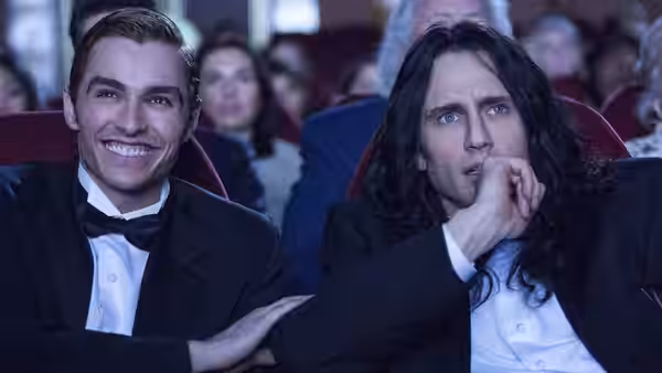 Greg (Dave Franco) smiling at Tommy (James Franco) in theater seats