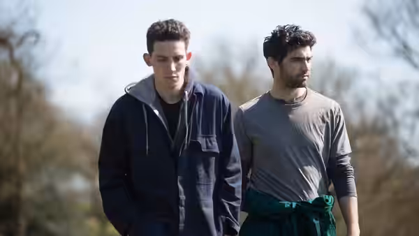 Johnny (Josh O'Connor) and Gheorghe (Alec Secăreanu) walking side by side outdoors