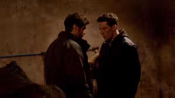 Johnny (Josh O'Connor) and Gheorghe (Alec Secăreanu) standing face to face indoors
