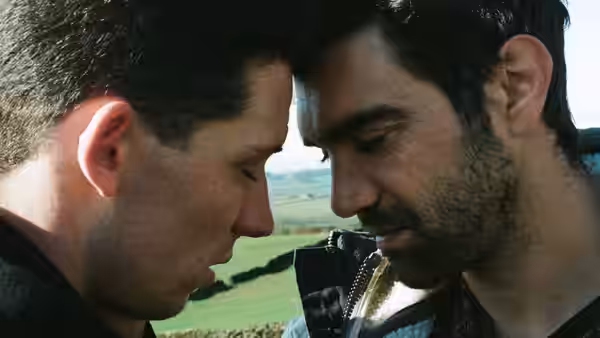 Johnny (Josh O'Connor) and Gheorghe (Alec Secăreanu) touching foreheads in a field
