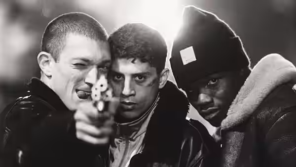 Vinz (Vincent Cassel) aiming a gun with Saïd and Hubert close by