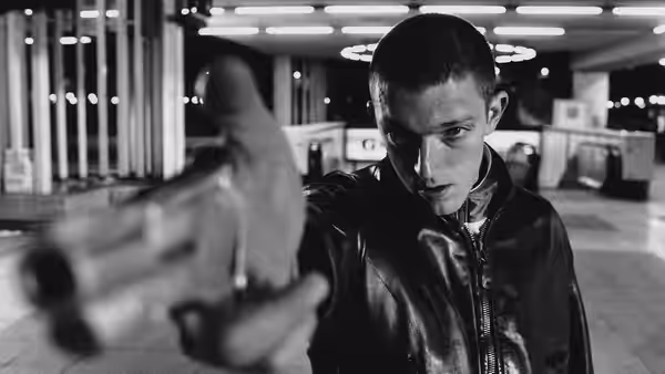 Vinz (Vincent Cassel) aiming a handgun inside a bright terminal