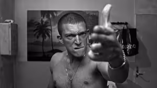 Vinz (Vincent Cassel) shirtless and pointing a gun straight ahead
