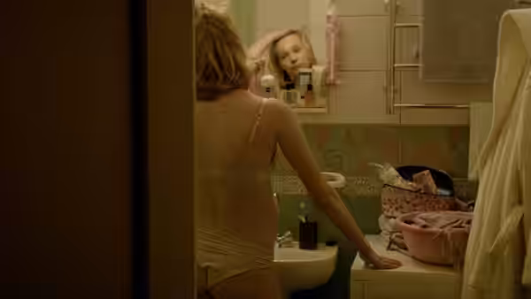 Woman in underwear stands in bathroom with mirror showing her reflection