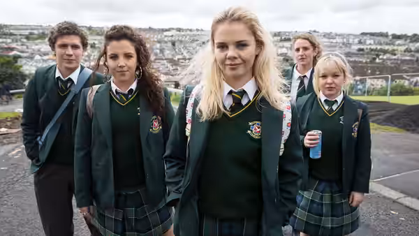 Erin Quinn and four classmates in green uniforms walking on a road