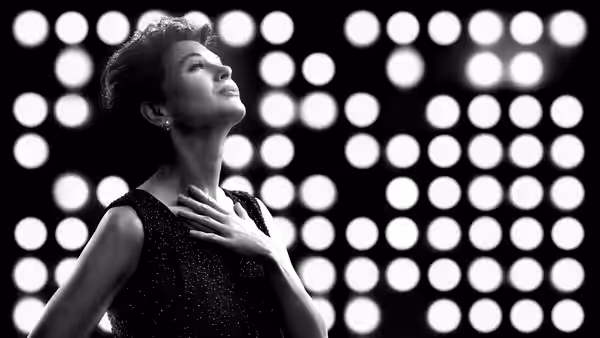 Judy Garland (Renée Zellweger) stands with hand on chest under stage lights