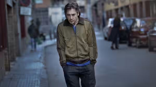 Uxbal (Javier Bardem) walks down a city street with hands in pockets