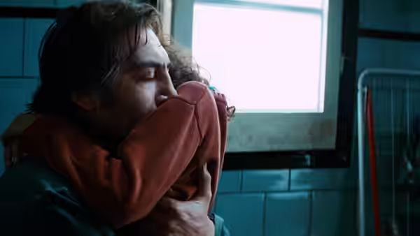 Uxbal (Javier Bardem) hugs his daughter tightly inside a tiled bathroom
