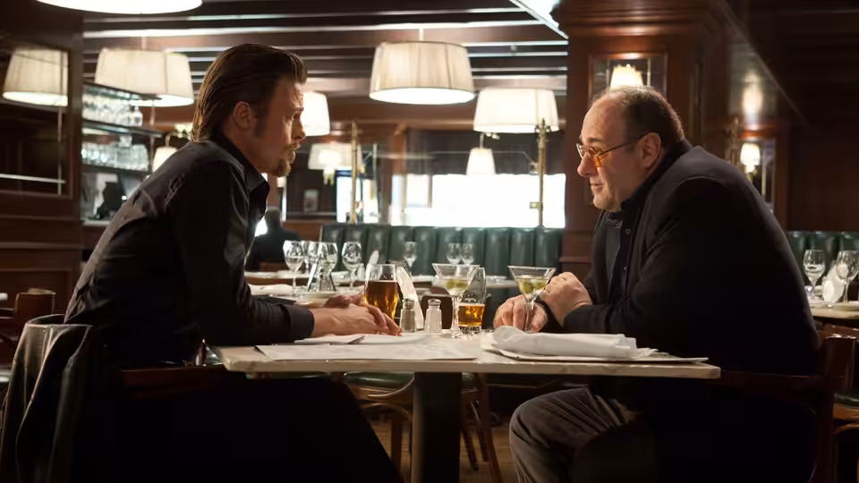 Jackie Cogan (Brad Pitt) and Mickey (James Gandolfini) talking over drinks at a restaurant table