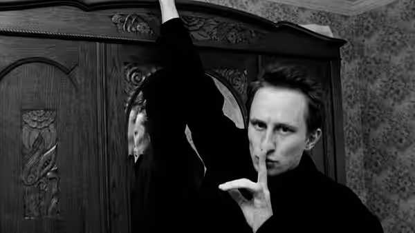 Ben (Benoît Poelvoorde) making a shushing gesture beside a wardrobe