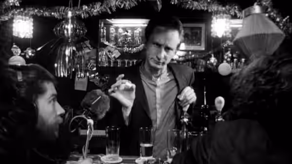 Ben (Benoît Poelvoorde) gesturing while standing at a decorated bar