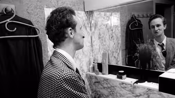 Ben (Benoît Poelvoorde) viewing his reflection in a bathroom mirror