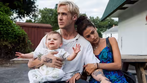 Luke Glanton (Ryan Gosling) holding a baby with Romina Gutierrez (Eva Mendes) beside him