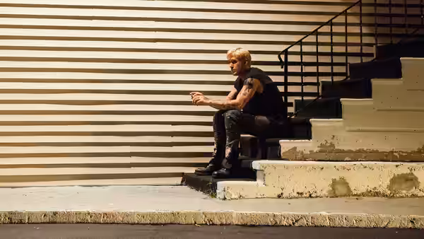 Luke Glanton (Ryan Gosling) sitting on concrete steps outside a building