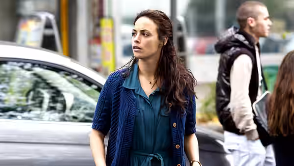 Marie (Bérénice Bejo) standing on a busy city street near parked cars