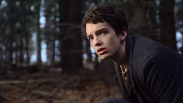 Jay Cavendish (Kodi Smit-McPhee) crouching in a forest with a surprised expression