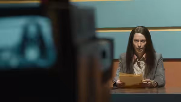 Christine Chubbuck (Rebecca Hall) reading papers at a news desk