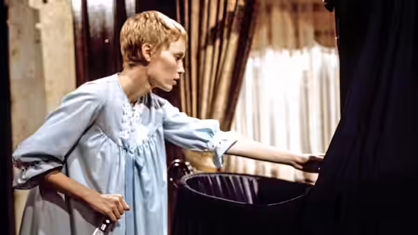 Rosemary Woodhouse (Mia Farrow) reaches toward a dark curtain in a bedroom