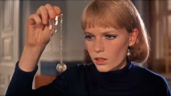 Rosemary Woodhouse (Mia Farrow) examines a pendant dangling from its chain