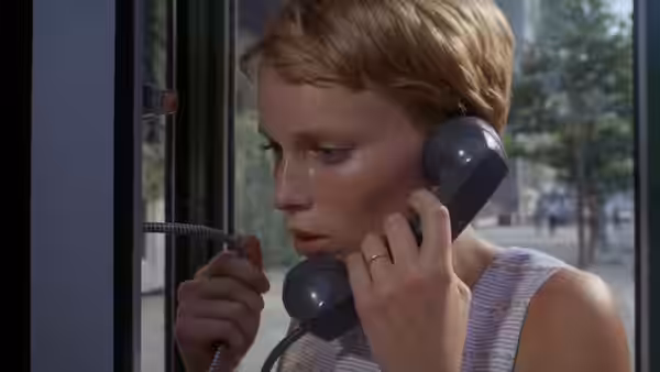 Rosemary Woodhouse (Mia Farrow) speaks on a telephone beside a window