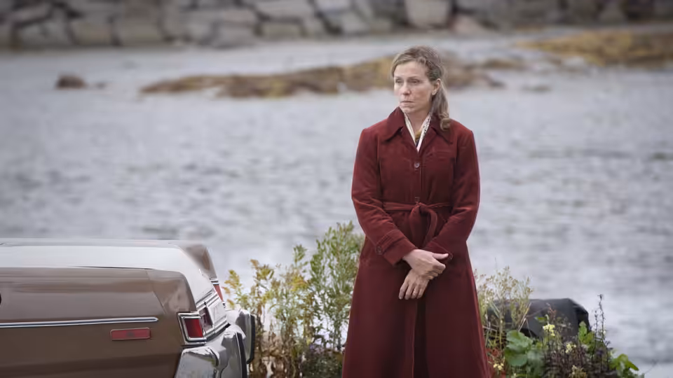 Olive Kitteridge (Frances McDormand) standing beside a car near the water