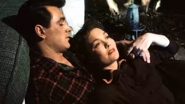 Ron Kirby (Rock Hudson) reclines beside Cary Scott (Jane Wyman) indoors