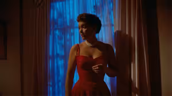 Cary Scott (Jane Wyman) stands by a blue-lit window in a red dress