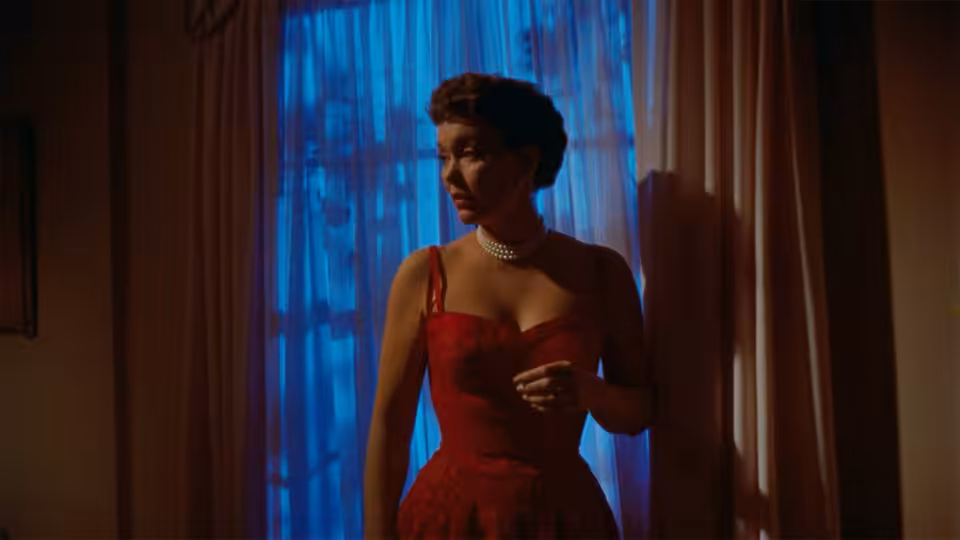 Cary Scott (Jane Wyman) stands by a blue-lit window in a red dress