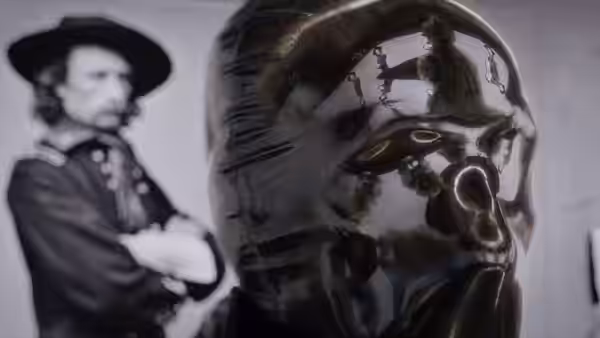 Glossy metallic mask reflecting a figure beside a black-and-white portrait of a man